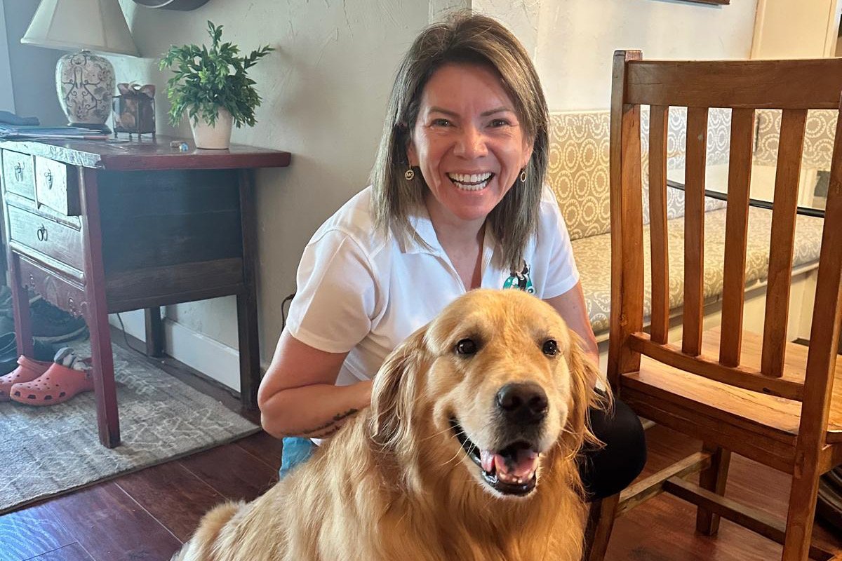 Smiling Mrs. AP Cleaning team member with a golden retriever in a client home